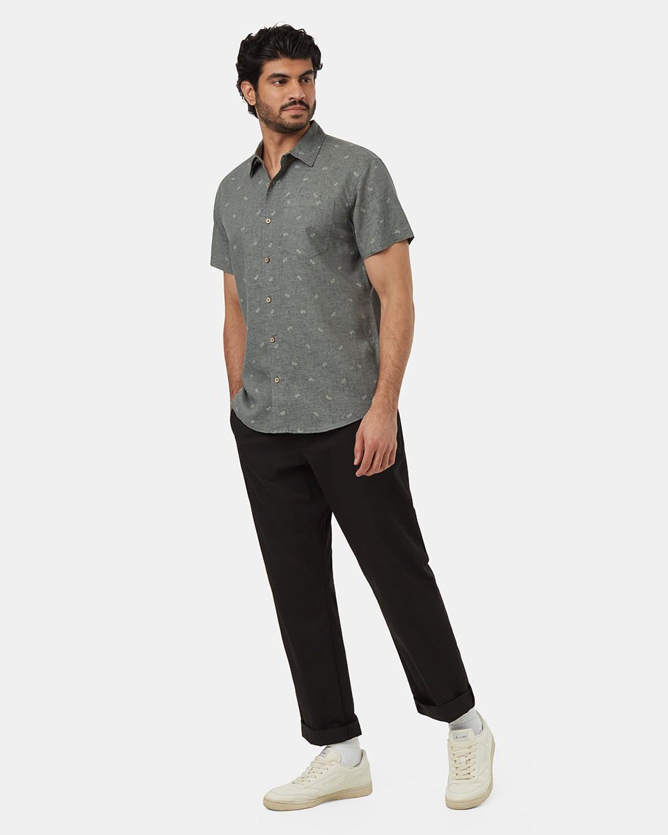 A man wearing a green short sleeve button up shirt with vans printed on it